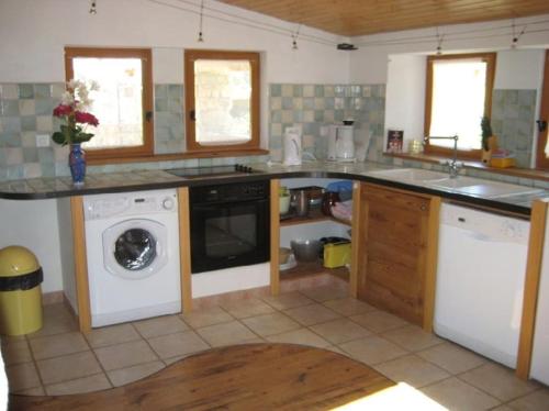 a kitchen with a washing machine and a washer at Gîte de l'Ouradou in La Cresse