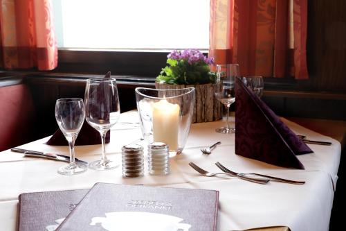 a table with wine glasses and a candle on it at Hotel an der Sonne & Restaurant Zum Schneiger in Schonwald im Schwarzwald
