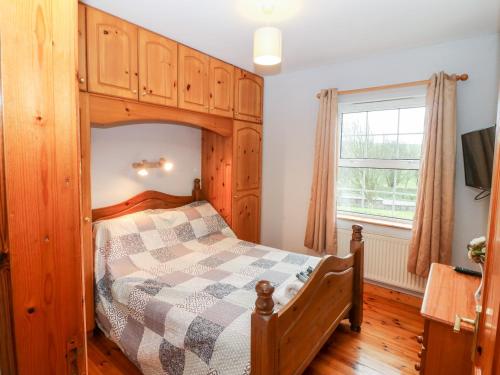 a bedroom with a wooden bed and a window at Raheen in Castletownshend