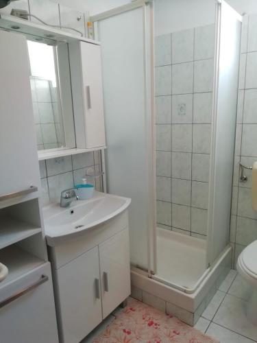 a white bathroom with a sink and a shower at Apartman Zlata in Ražanac