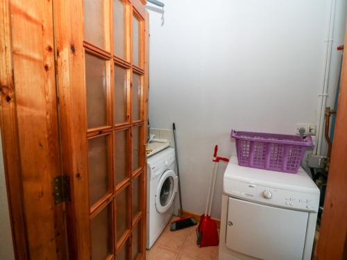 a laundry room with a washing machine and a purple basket on top at Raheen in Castletownshend