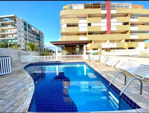 une piscine en face d'un grand bâtiment dans l'établissement VARANDA GOURMET c churrasqueira-3 quartos- Wi-fi, à Bertioga