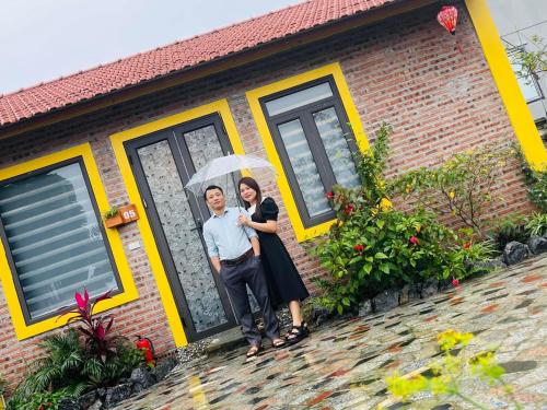 a man and woman standing in front of a house with an umbrella at Ninh Binh Royal Homestay in Ninh Binh