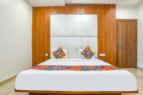 een slaapkamer met een groot wit bed met kleurrijke kussens bij FabHotel Right Choice in Indore