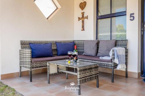a patio with a couch and a table with wine glasses at Little Haven in St Helena Bay