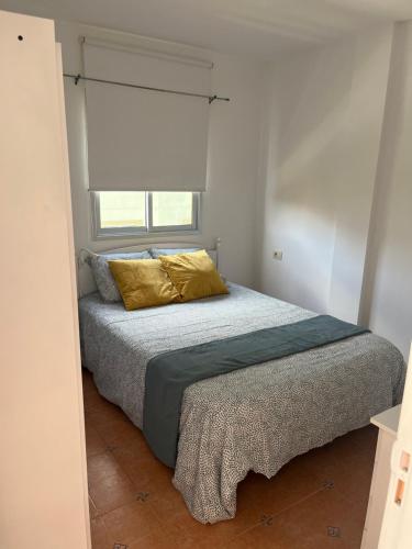a bedroom with a bed with a yellow pillow at Estudio Las Algas in Los Abrigos