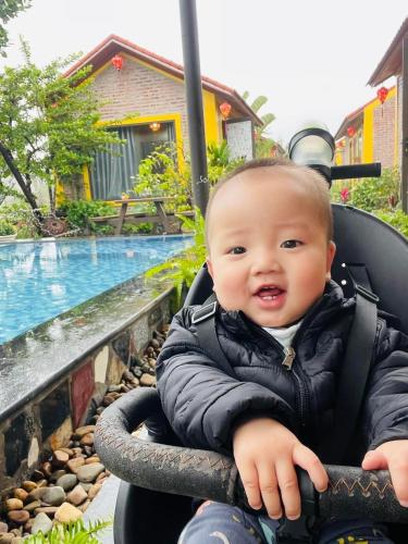 a baby sitting in a stroller next to a pool at Ninh Binh Royal Homestay in Ninh Binh