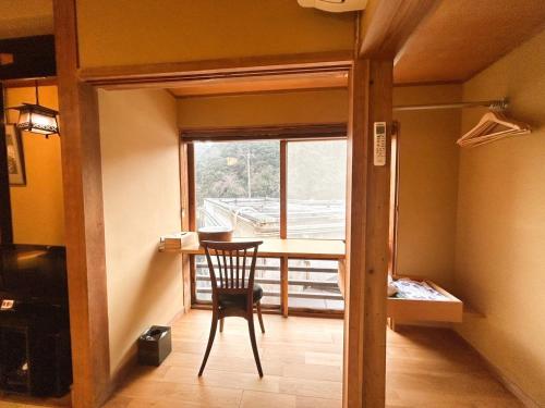 a room with a chair and a table and a window at Arifuku Onsen Yoshidaya in Gotsu