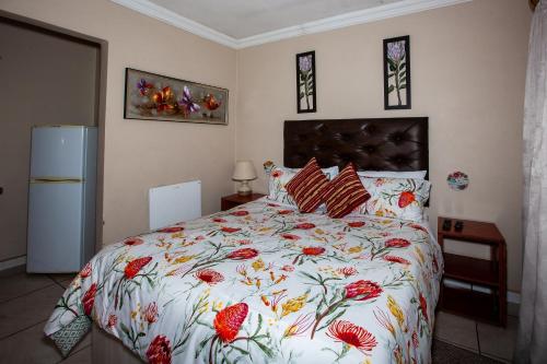 a bedroom with a large bed with a floral bedspread at Invite Guest House - Self Catering Accommodation in Vanderbijlpark in Vanderbijlpark