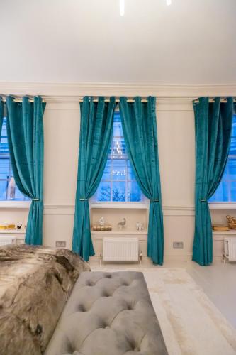 a room with blue curtains and a large bed in front of a window at Haus of Mason in London