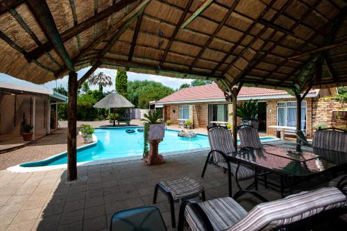 a patio with a table and chairs and a pool at Invite Guest House - Self Catering Accommodation in Vanderbijlpark in Vanderbijlpark