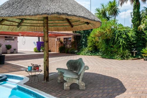 a chair and an umbrella next to a pool at Invite Guest House - Self Catering Accommodation in Vanderbijlpark in Vanderbijlpark