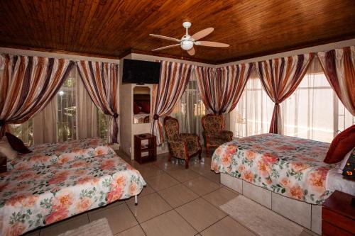 a bedroom with two beds and a ceiling fan at Invite Guest House - Self Catering Accommodation in Vanderbijlpark in Vanderbijlpark