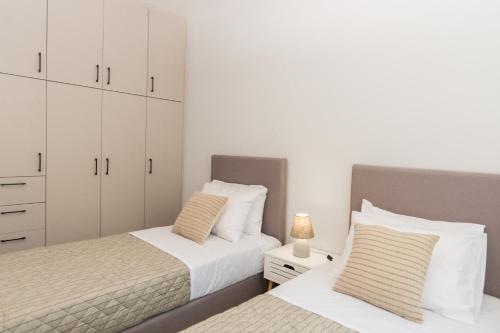 two beds in a bedroom with white cabinets at Al Santo Apartments in Zakynthos