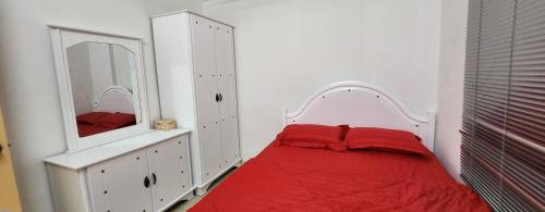 1 dormitorio con cama roja y espejo en DSAF Family Homestay Pandan Indah, en Ampang