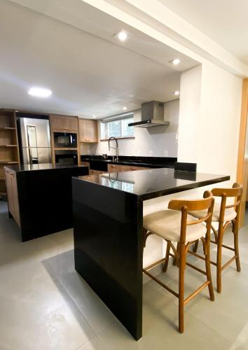 a kitchen with a black island with two chairs at Pousada O Cantinho da Raposa in Monte Verde