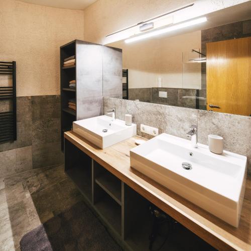 a bathroom with two sinks and a mirror at Camping Dreiländereck Blockhütten & Apartments in Ried im Oberinntal