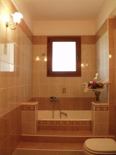 a bathroom with a tub and a toilet and a window at Hotel Archontiko Dimitra in Vergina