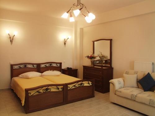 a bedroom with a bed and a couch and a mirror at Hotel Archontiko Dimitra in Vergina
