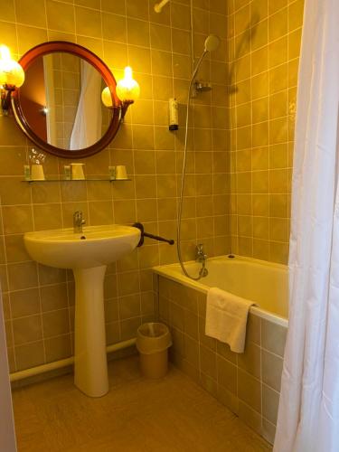 La salle de bains est pourvue d'un lavabo, d'un miroir et d'une baignoire. dans l'établissement Hostellerie Du Chateau, à Châteauneuf