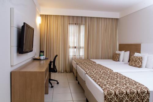 a hotel room with two beds and a television at Quality Hotel & Suítes São Salvador in Salvador
