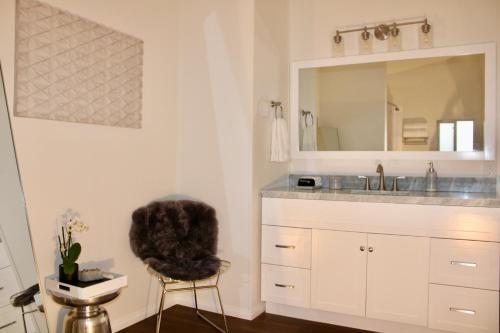 ein Badezimmer mit einem Waschbecken, einem Spiegel und einem Stuhl in der Unterkunft Death Valley Hot Springs 1 Bedroom in Tecopa