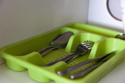 a green tray filled with utensils on a counter at Pousada Guaricana in Pontal do Paraná