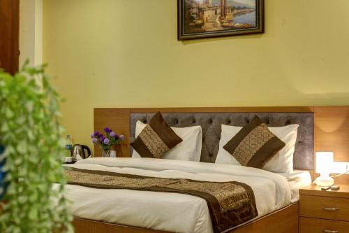 a bedroom with a large bed with white sheets and pillows at Hotel TMS Grand in New Delhi