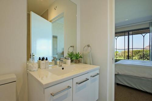 a bathroom with a sink and a mirror and a bed at 9 The Village in Hout Bay