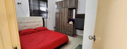 a small bedroom with a red bed and a dresser at DSAF Family Homestay Pandan Indah in Ampang