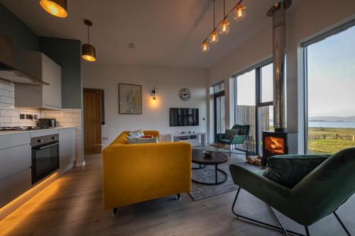 a living room with a yellow couch and a kitchen at Silverwood Waternish in Portree