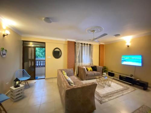 a living room with a couch and a flat screen tv at Lovely and homely 2 bedroom Serviced Apartment in Kilifi