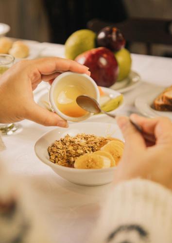 a person holding a bowl of food with a spoon at Pousada O Cantinho da Raposa in Monte Verde