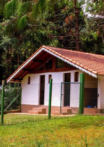a small white building with a fence in the grass at Pousada O Cantinho da Raposa in Monte Verde