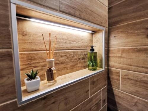 a bathroom with a shelf with two bottles and a plant at Himosranta Suites in Jämsä