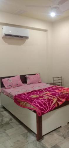 a bedroom with a bed with a pink comforter at Hotel A Star & Restaurant By WB Inn in Ghaziabad