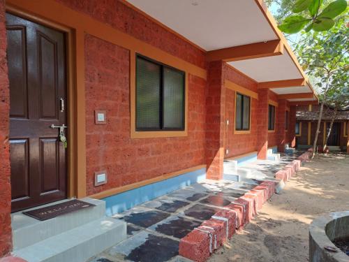 a brick building with a door and a stone walkway at Palm Beach Resort in Kumta