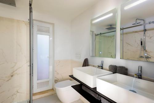 a white bathroom with two sinks and a toilet at AlohaMundi Adriano in Seville