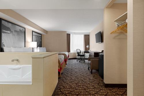 a hotel room with two beds and a desk at Ramada By Wyndham Niagara Falls near the Falls in Niagara Falls