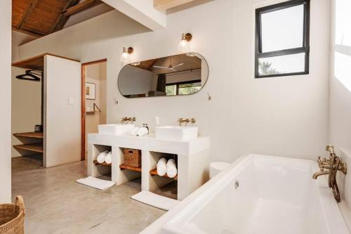 a white bathroom with two sinks and a tub at Makanyane Lodge in Matlhagame