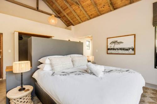 Makanyane Lodge في Matlhagame: غرفة نوم مع سرير أبيض كبير في غرفة