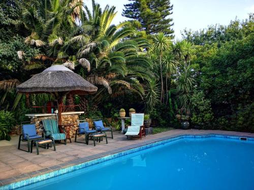 a swimming pool with chairs and a gazebo next to a swimming pool at Santika Garden Cottage Stellenbosch in Stellenbosch