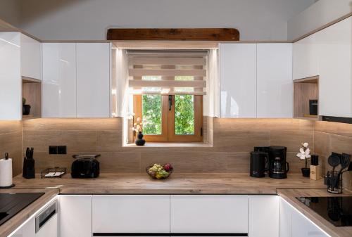 a kitchen with white cabinets and a window at Stone villa Halepa panoramic view, private pool,big garden & quiet in Néon Khoríon