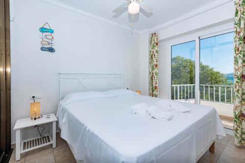 a white bedroom with a bed and a window at On The Beach Voramar by Sealand Villas in Port de Pollensa