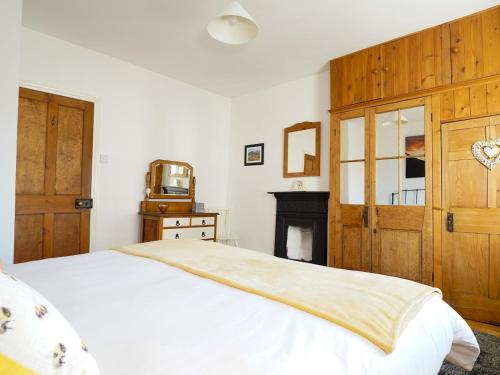 a bedroom with a white bed and a wooden door at Pass the Keys Cosy Cottage in Corris One wellbehaved dog welcome in Machynlleth