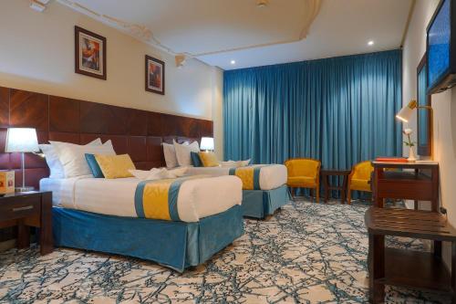 ein Hotelzimmer mit 2 Betten, einem Tisch und Stühlen in der Unterkunft Saraya Al Deafah Hotel in Mekka