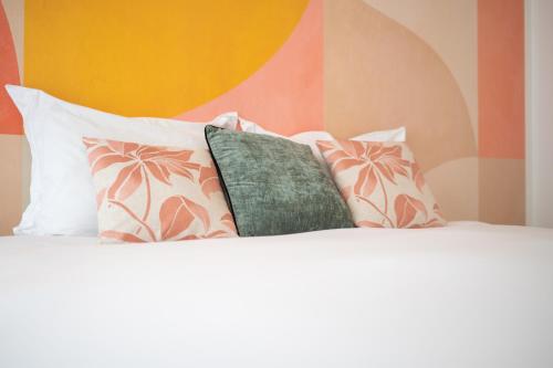 - un lit avec des oreillers blancs et un oreiller vert dans l'établissement Superbe appartement avenue de Champagne + parking, à Épernay
