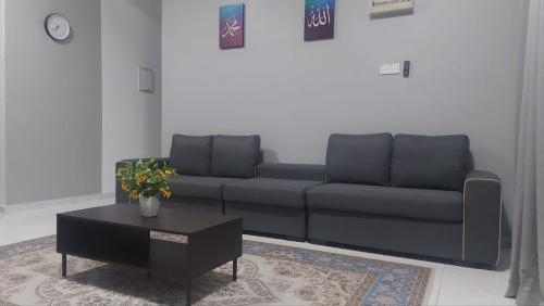 a living room with a black couch and a coffee table at Desaku Homestay in Kapar