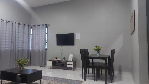 a living room with a table and chairs and a television at Desaku Homestay in Kapar