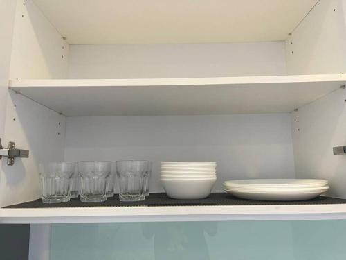a shelf with bowls and plates and glasses on it at Teega Suites Seaview by VDO Homestay in Nusajaya
